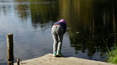 Little girl walks and plays at coast of the lake Stock Footage