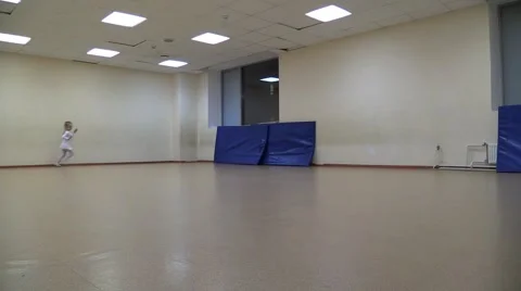 Little girl in white ballet gown funny running around in an empty sport gym Stock Footage 59108335