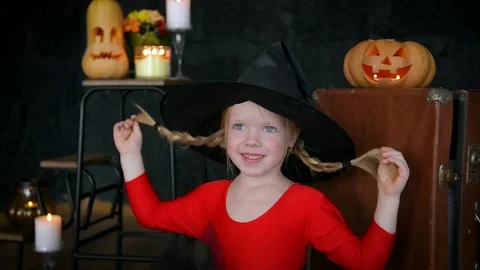 A little girl, a witch, in a hat, eats sweets and scares the camera. Stock Footage 80636321