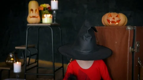 A little girl, a witch, in a hat, eats sweets and scares the camera. Stock Footage 80636593