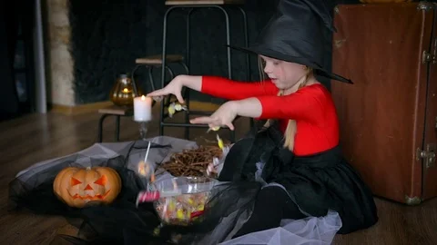A little girl, a witch, in a hat, eats sweets and scares the camera. Stock Footage 80636705