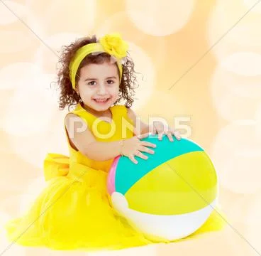 Little girl in yellow dress with big ball Stock Photos