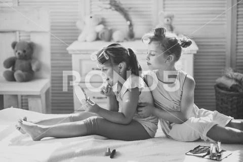 Little girls with curlers play with makeup accessories Stock Photos