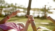 Little Girls Lie On The Grass In The Park, The Sisters Play Games With Fingers Stock Footage