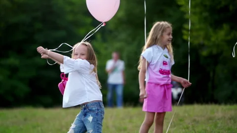Little girls playing with baloons outside. Cute sunny kids dance with baloons Stock Footage 148829188