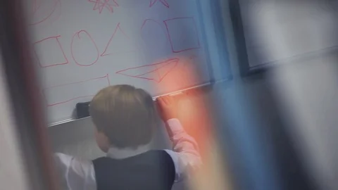 Little guy in school uniform standing near blackboard, drawing geometrical Stock Footage 98553425