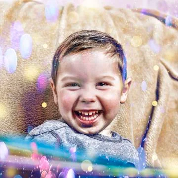 Little happy boy laughs while sitting on sofa at home in Christmas interior. Stockfoto's