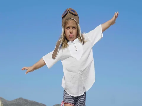 Little happy girl in aviator's cap smiling and playing, in white T-shirt, blue s Stock Footage