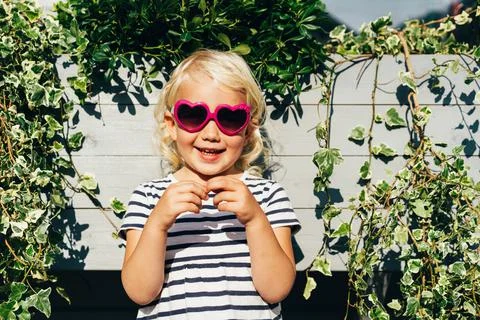 Little happy laughing blonde girl in sunglasses looks at the camera. Stock Photos