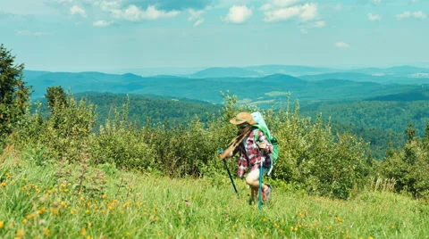 Little hiker girl in sunglasses with backpack going up the hill on mountains Stock Footage