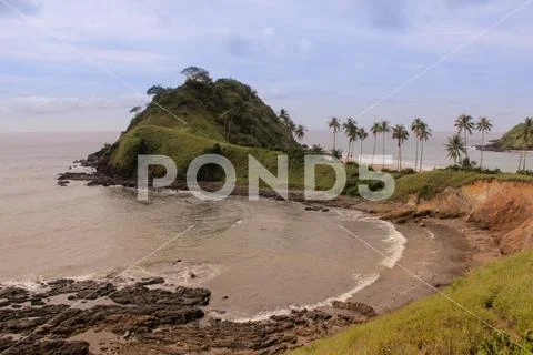 Little hill at the end of a white beach with palm trees Stock Photos