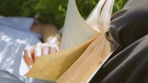 A little industrious guy with dirty hands reads an old book on the pasture 스톡 동영상 77978245