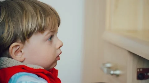 Little kid with blue eyes while watching TV in living room. Vidéo 128745008