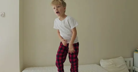 Little kid bouncing happily on soft bedding, Youthful child playing 스톡 동영상 321622211