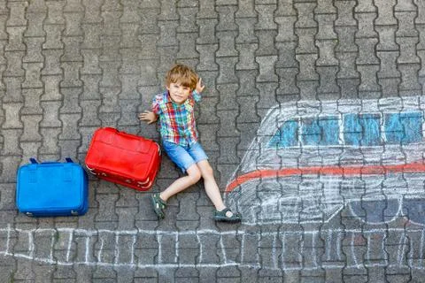 Little kid boy having fun with fast train picture drawing with colorful chalks Stock Photos