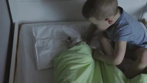 Little kid boy preparing to sleep covering his loving toy with green blanket Stock Footage 240346925