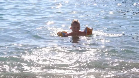 Little kid cheerfully swimming in bright blue seawater. Stock Footage