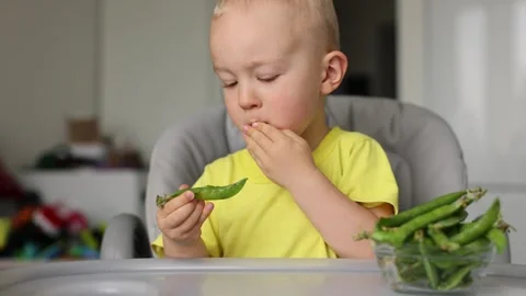 Little kid eats fresh green peas. 4R Stock Footage 322028756