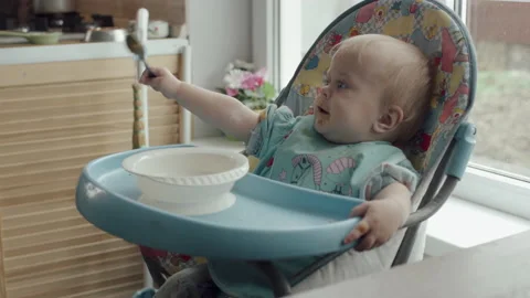 Little Kid Eats Himself Spoon Baby Food Sitting In Baby Chair At Home Stock-Footage 143810284