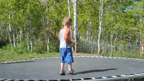 Little kid gets on the trampoline does a trick and gets off. Stock Footage 89952146