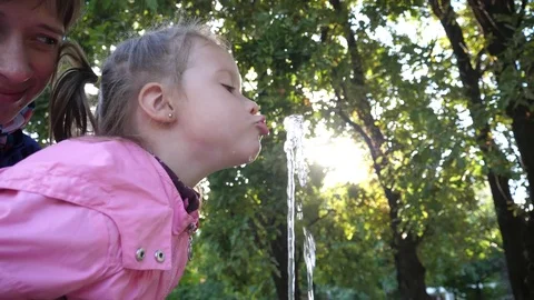 Little kid girl funny drink chase catch the water jet of drinking fountain water Stock Footage