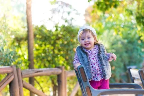 Little kid girl standing in a chair and smiling outdoors. Stock Photos