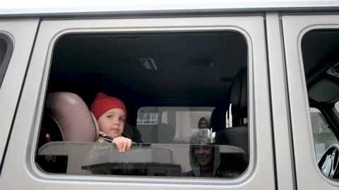 Little kid in hat and jacket smiles to mother sitting in car Video stock 154389840