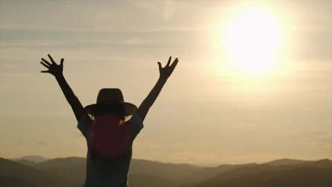 Little kid in hat raises his hands up on mountains background during sunset Stock Footage 246825850