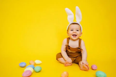 Little kid joyful smiling boy with bunny ears on yellow studio background, Happy Stock Photos