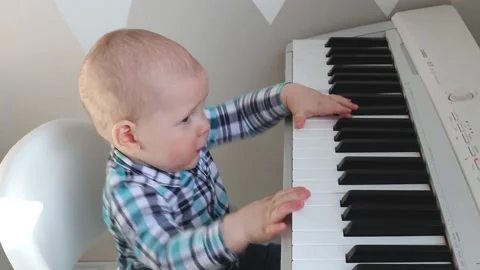 A little kid knocks his hands on the keys of an electronic piano Stock Footage 149491650