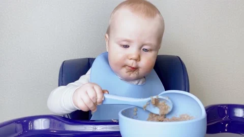 Little kid learning to eat by himself with blue spoon. Stock Footage 177283544