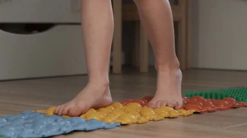 Little kid making exercises on the rubber orthopedic puzzle mat Stock Footage 233903211