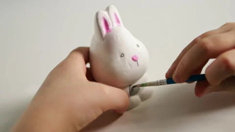 Little kid painting ceramic easter bunny figure. Child making DIY Stock Footage 189937721