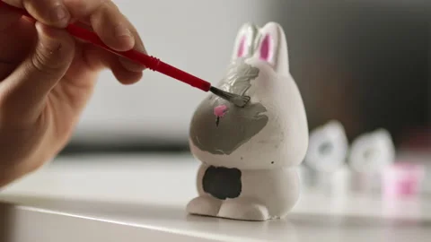 Little kid painting ceramic easter bunny figure. Child making DIY crafts Stock Footage 189940043