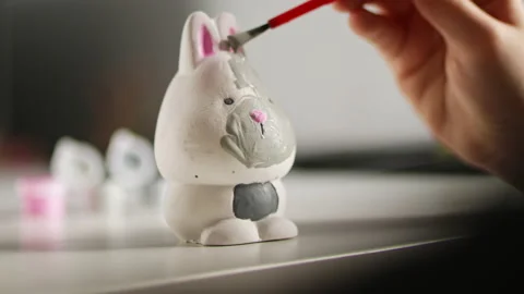Little kid painting ceramic easter bunny figure. Child making DIY Stock Footage 189940752