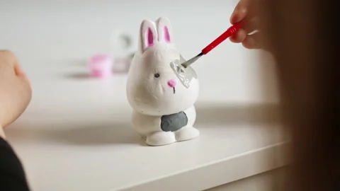 Little kid painting ceramic easter bunny figure. Child making DIY craft Stock Footage 189941294