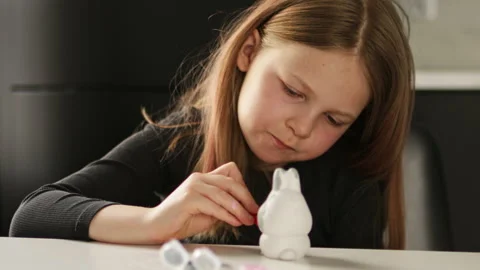 Little kid painting ceramic easter bunny figure Stock Footage 189944259