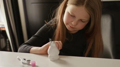 Little kid painting ceramic easter bunny figure. Child making DIY Stock Footage 189947132