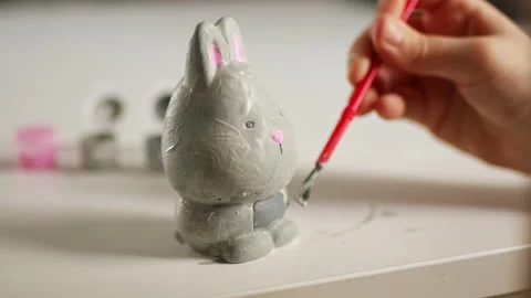 Little kid painting ceramic easter bunny figure. Child making DIY Stock Footage 189950136