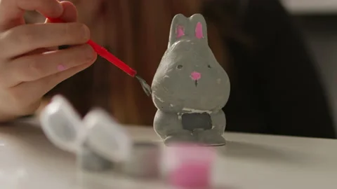 Little kid painting ceramic easter bunny figure. Child making DIY Stock Footage 189950461