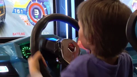 Little kid playing auto simulator video arcade game Stock Footage 76872926