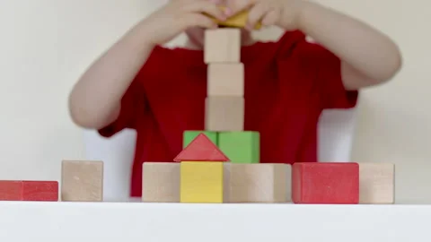 Little kid playing at table with eco wooden colorful cubes 動画素材 199574418