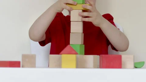 Little kid playing at table with eco wooden colorful cubes Видео 199574608