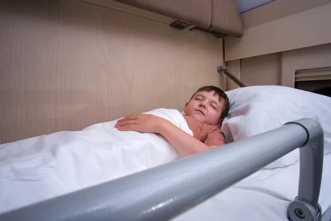 Little kid sleeping on bunk bed in train carriage. Caucasian boy resting du.. Stock Photos
