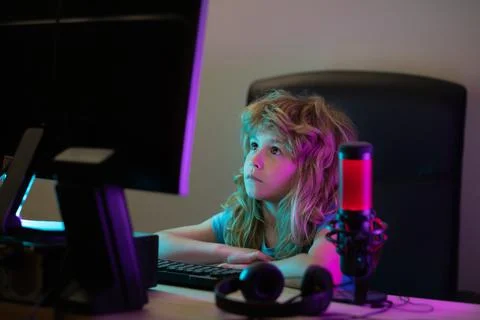 Little kid using desktop pc by night, child boy illuminated by the blue light of Stock-Fotos