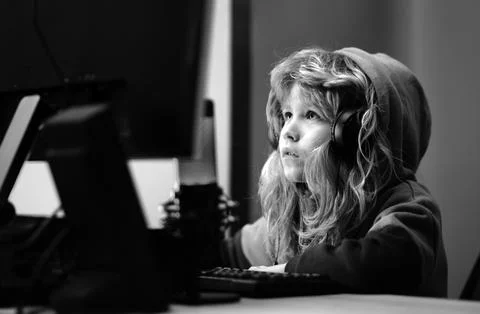 Little kid using desktop pc by night, child boy illuminated by the blue light of Stock-Fotos