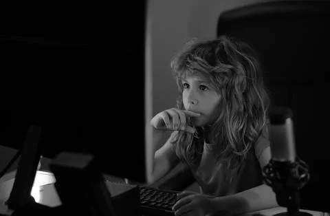 Little kid using desktop pc by night, child boy illuminated by the blue light of Stock-Fotos