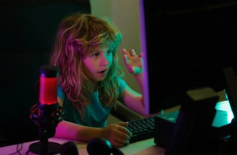 Little kid using desktop pc by night, child boy illuminated by the blue light of Foto stock