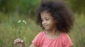 Little lonesome kid standing in garden and playing with small white flower 4k or 4k+ Resolution