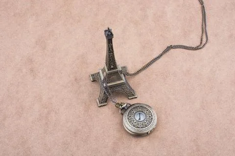 Little model Eiffel Tower and a pocket watch on brown background Foto stock